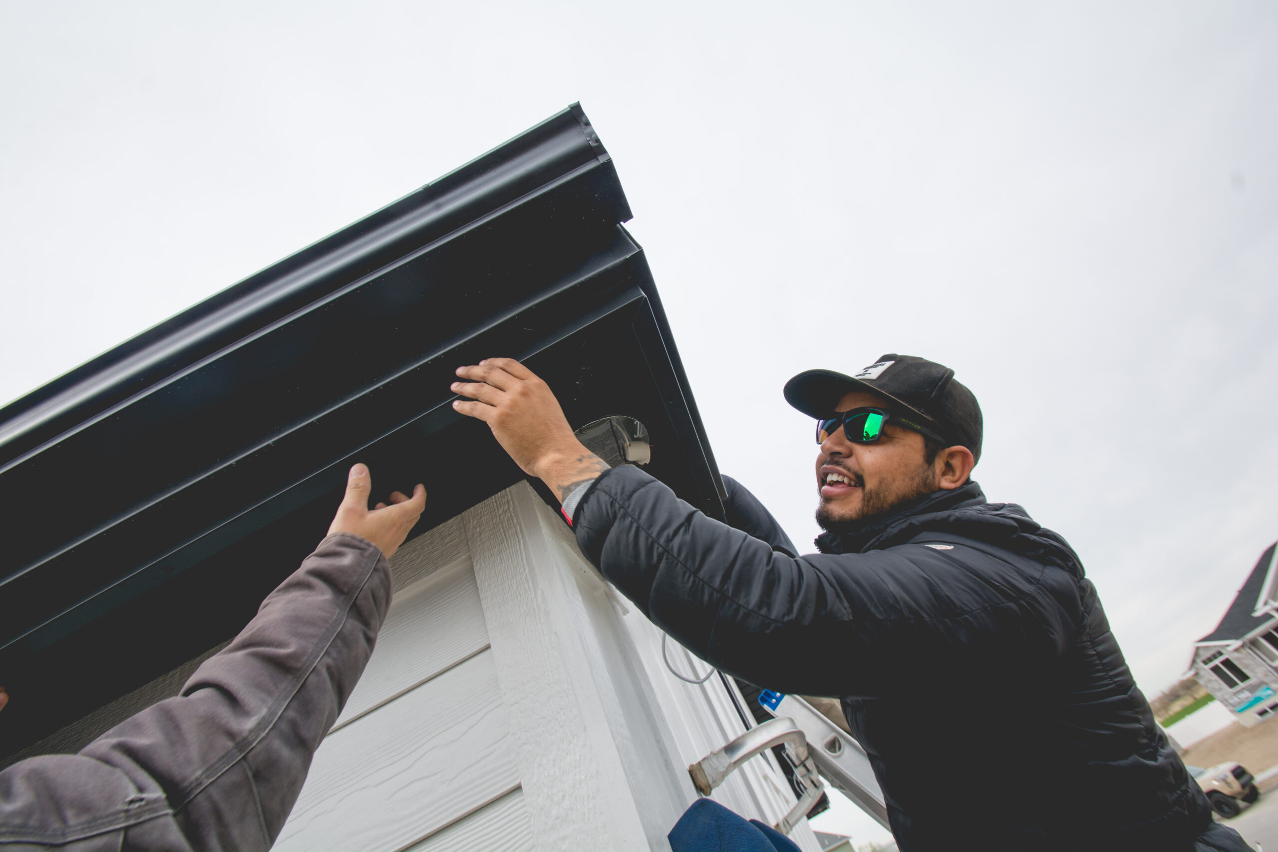 Two workers from Trimlight of Long Island installing programmable lighting system on a house.