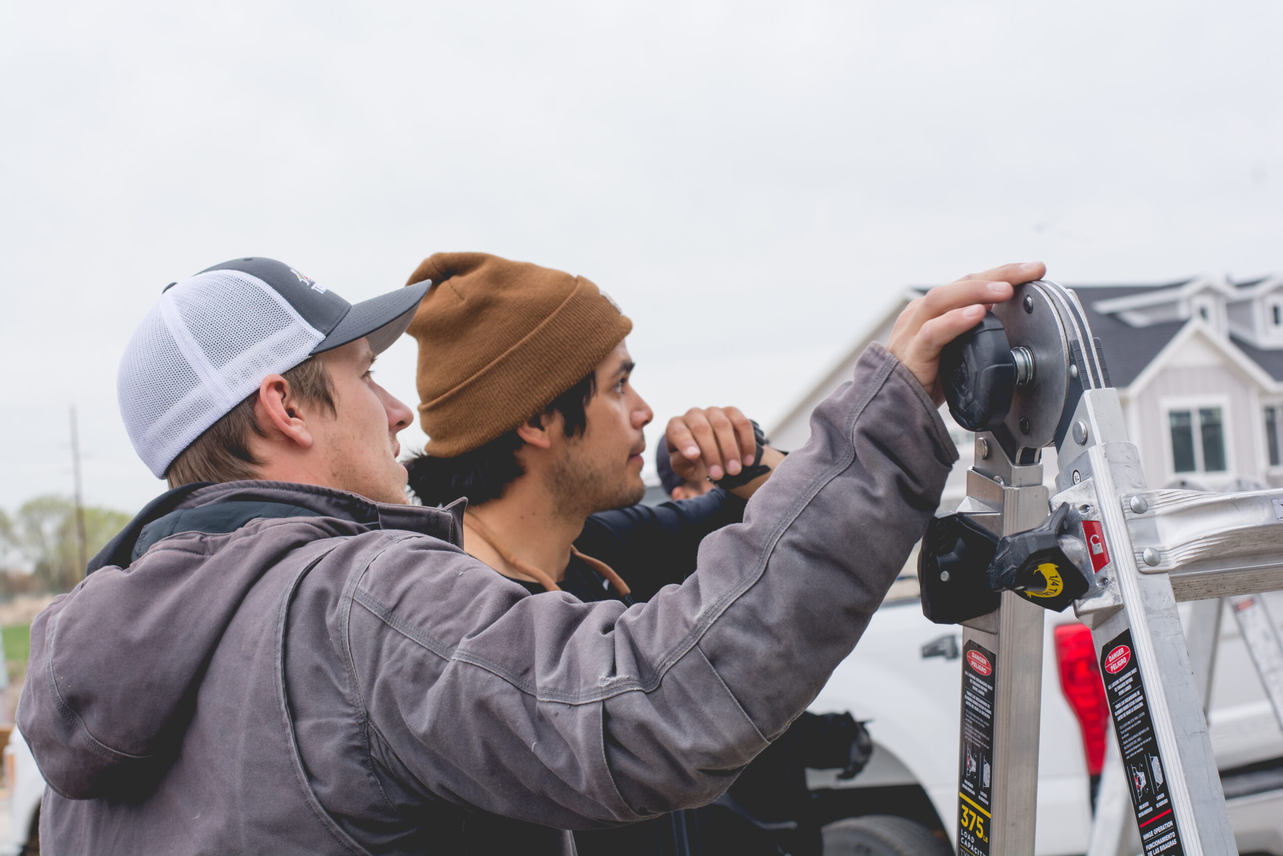 Two workers from Trimlight of Long Island installing programmable lighting system on a house.